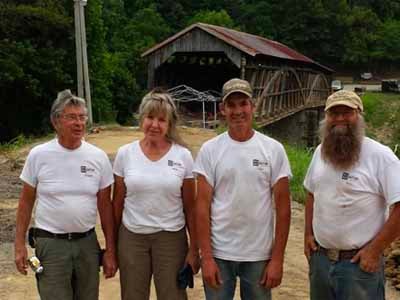 Four crew members standing in front of Beechfork covered bridge before restoration