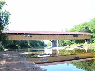 Blair covered bridge exterior spanning river with summer foliage