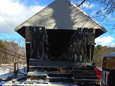 Blair covered bridge portal in winter showing deteriorated siding and snow