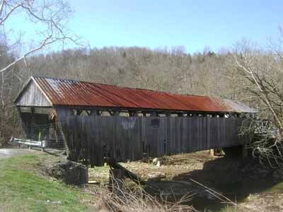 Cabin Creek covered bridge exterior showing weathered siding and rusted metal roof
