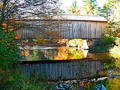 Corbin covered bridge reflected in calm river surrounded by autumn trees