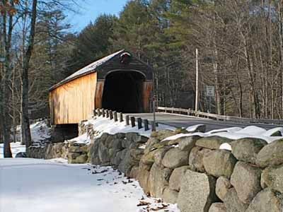 Corbin covered bridge in winter with snow on stone wall and roadway