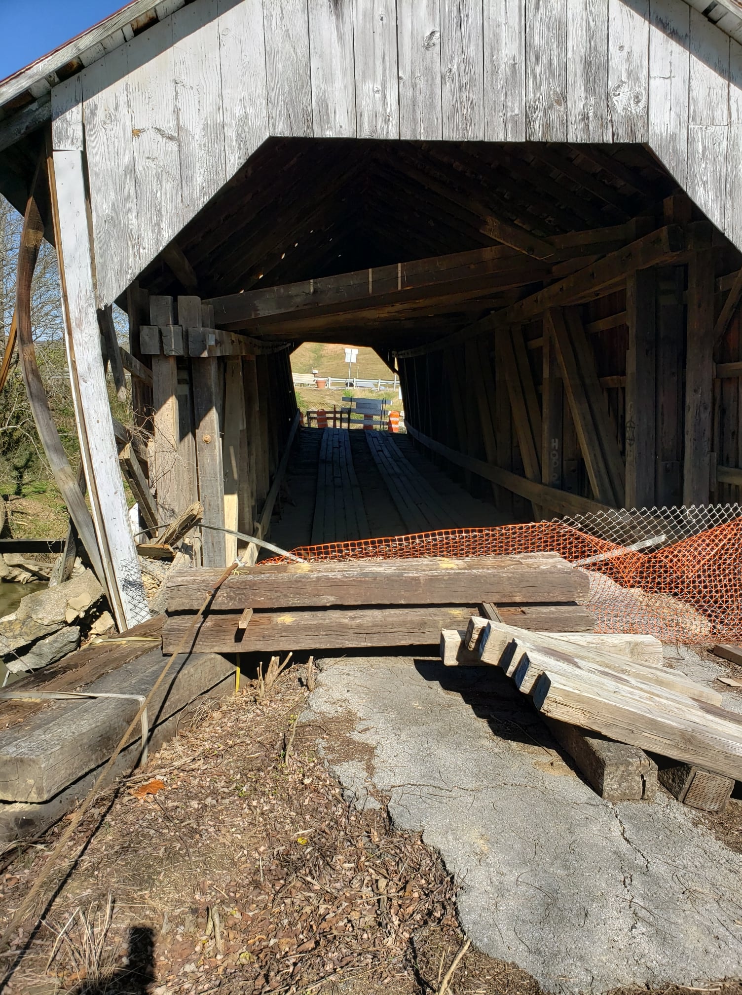Grange City covered bridge interior looking through with orange construction fencing and displaced timbers