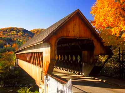 Middle covered bridge exterior with autumn foliage and mountain backdrop