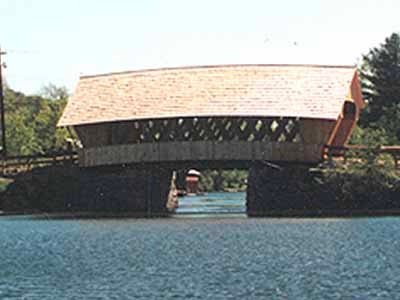 Squam River covered bridge exterior view from the water showing lattice truss siding