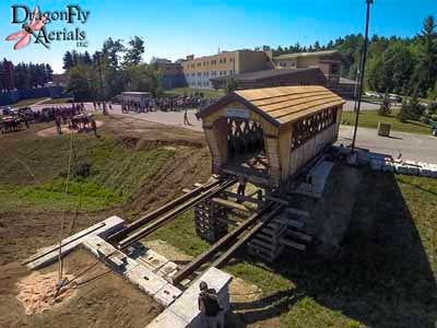 Aerial view of Stoney Morrill covered bridge being set onto abutments with crowd watching