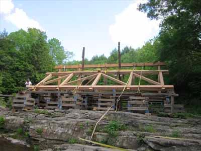 Tuscarora covered bridge mid-construction with siding and ladder on rock abutment