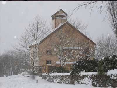 Completed Coleman stone barn with cupola in winter snowstorm