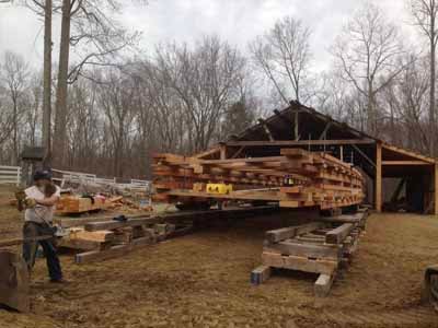Perry barn under construction in winter with timber frame and stacked lumber