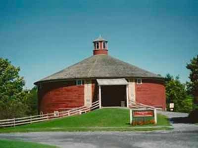 Shelburne Museum round barn exterior with red siding, cupola, and white fence