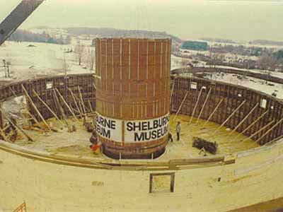 Shelburne Museum round barn interior under construction in winter with signage visible